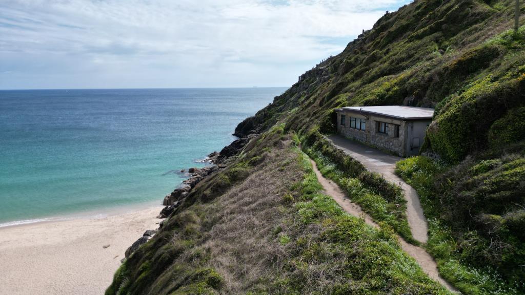 Lot: 69 - DETACHED RESIDENTIAL PROPERTY ENJOYING BREATHTAKING SEA VIEWS IN TRULY STUNNING LOCATION - Drone photo showing property, patio area, footpath and part of the beach